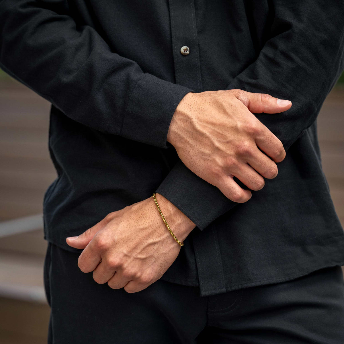 Person wearing a black shirt with hands clasped in front, blurred background