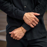 Person wearing a black shirt with hands clasped in front, blurred background