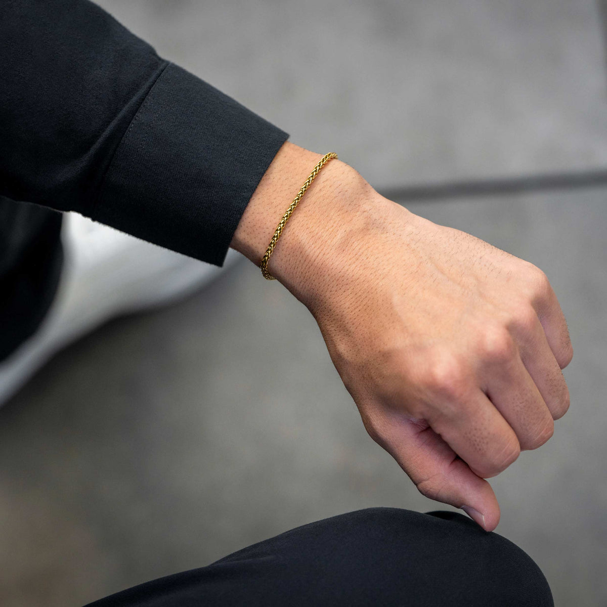 Hand wearing a gold bracelet on a blurred background