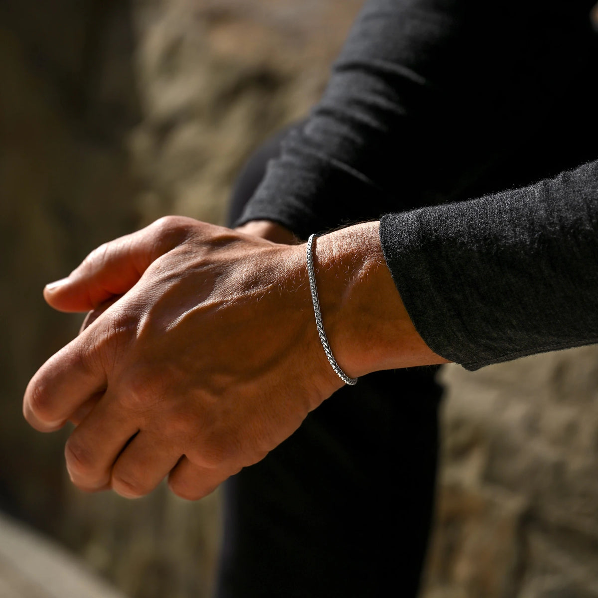 Close-up of a person's hands with a bracelet against a blurred natural background