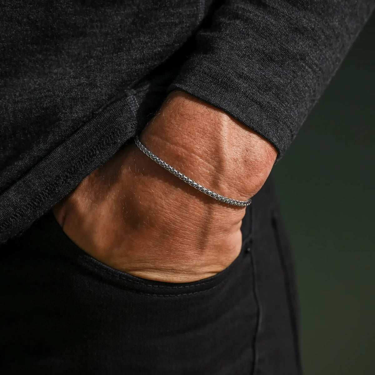 Close-up of a person wearing a silver bracelet on a dark background