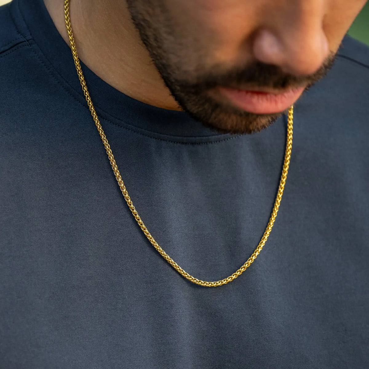 Gold chain necklace worn by a person on a dark blue shirt