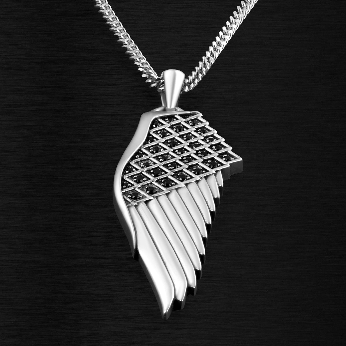 Silver wing-shaped pendant with black stones on a dark background