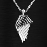 Silver wing-shaped pendant with black stones on a dark background