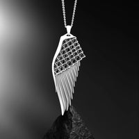 Silver wing-shaped pendant with black stones on a dark background