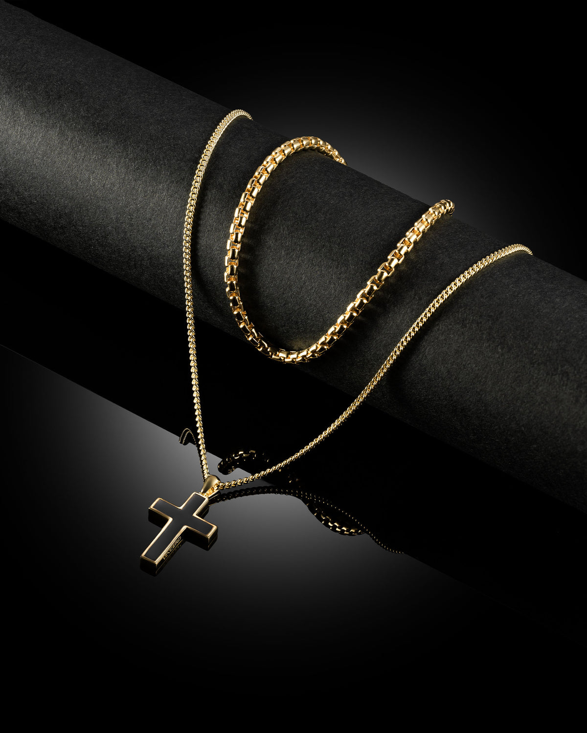 A gold-plated cross pendant on a two-layer gold box chain necklace against a white background.
